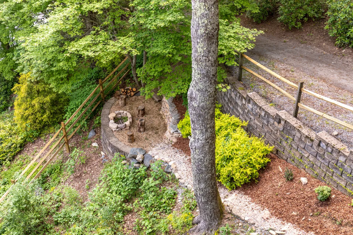 A welcoming fire pit area bordered by stone walls and surrounded by greenery, inviting guests to gather, socialize, and enjoy the outdoors. The scene suggests warmth, camaraderie, and the promise of memorable evenings spent under the stars.