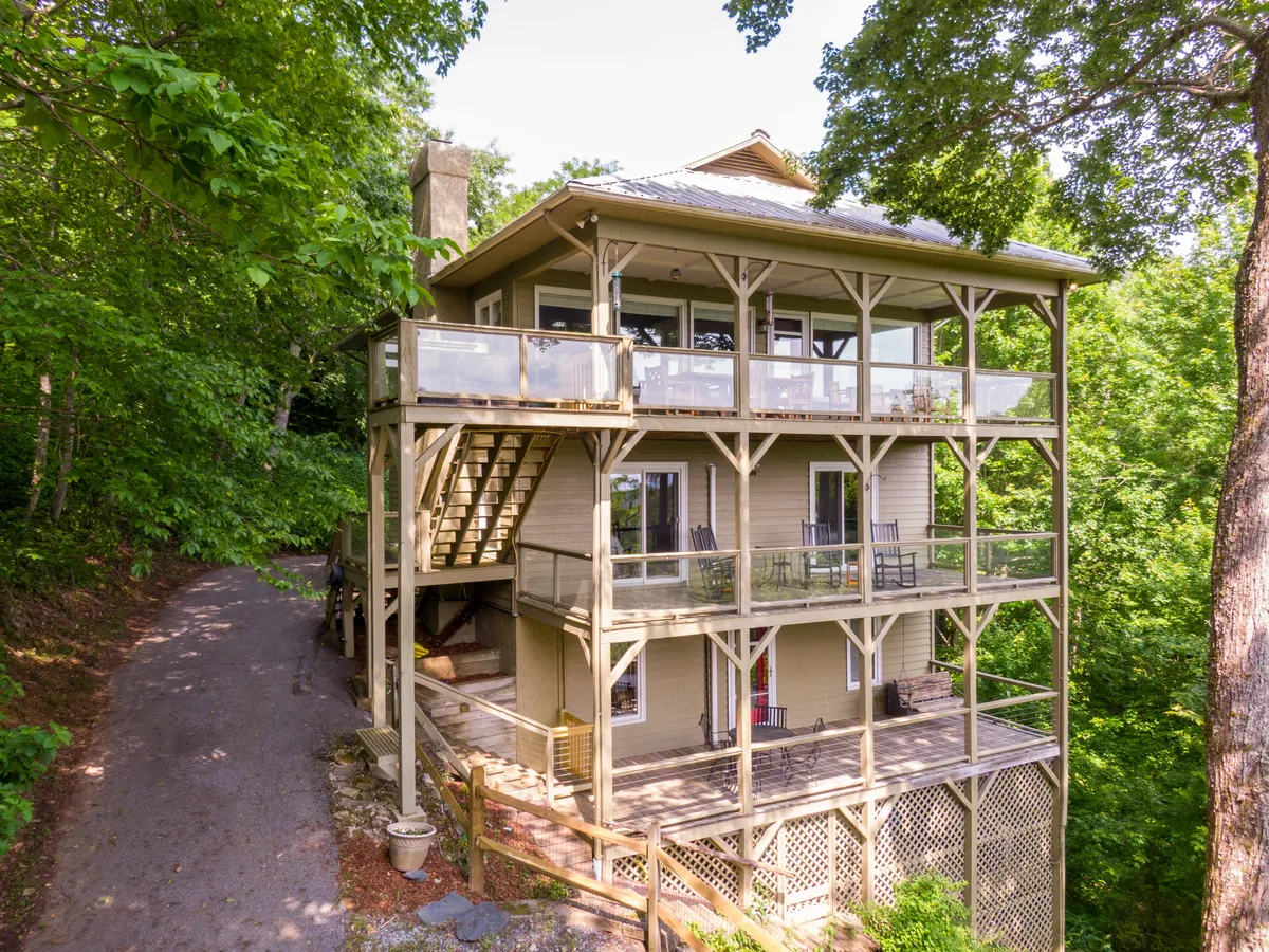 This exterior view presents the multi-level structure of Sunset Vista, highlighting its large decks and the surrounding greenery. The spacious outdoor areas are perfect for relaxing, social gatherings, and appreciating sunset or stargazing views, all while immersed in tranquil natural surroundings.