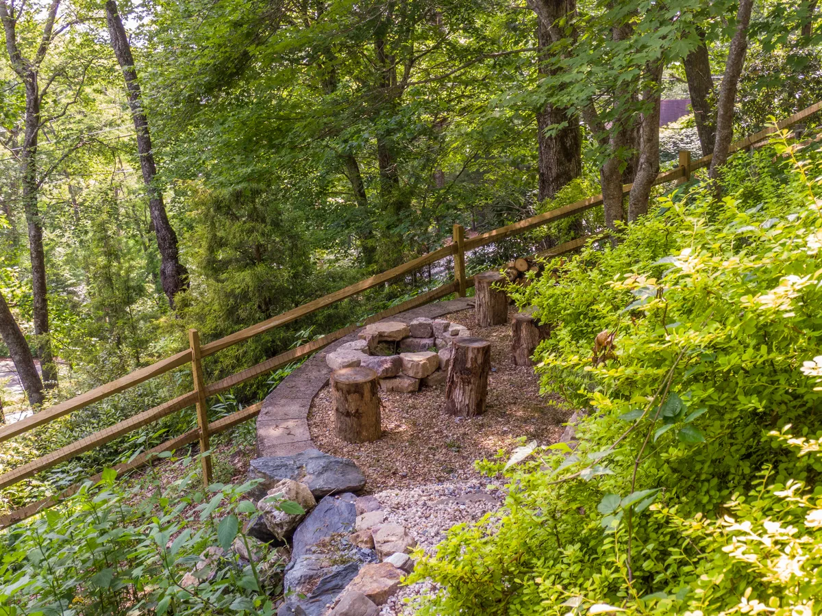 This exterior scene highlights a stone seating area encircled by greenery and a wooden fence. It's designed for cozy gatherings around a fire pit, stargazing, or simply unwinding in the tranquil mountain air, offering a taste of the outdoor experiences available to families and guests.